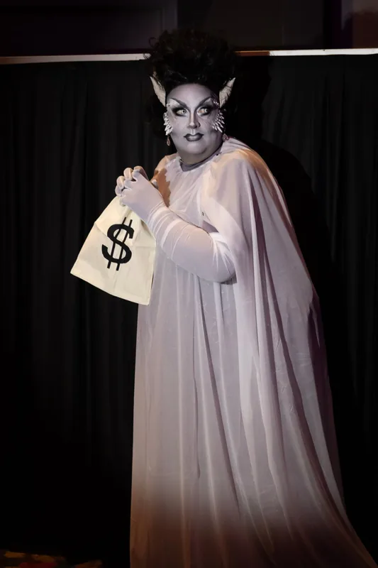 @thelolapalooza as a Bride of Frankenstein in a white gown, clutching a money bag.